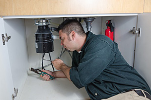 Paul is under the sink working on a garbage disposal repair in Ellicott City