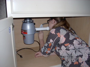 a woman is checking the garbage disposal because it's making weird noises 